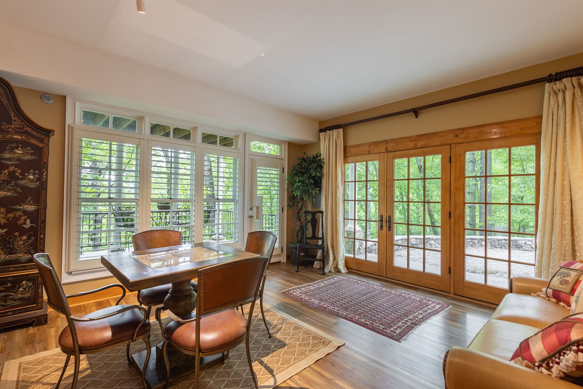 The spacious lower-level king suite offers a private retreat with cozy seating, wooded views, and direct access to the outdoor deck area.