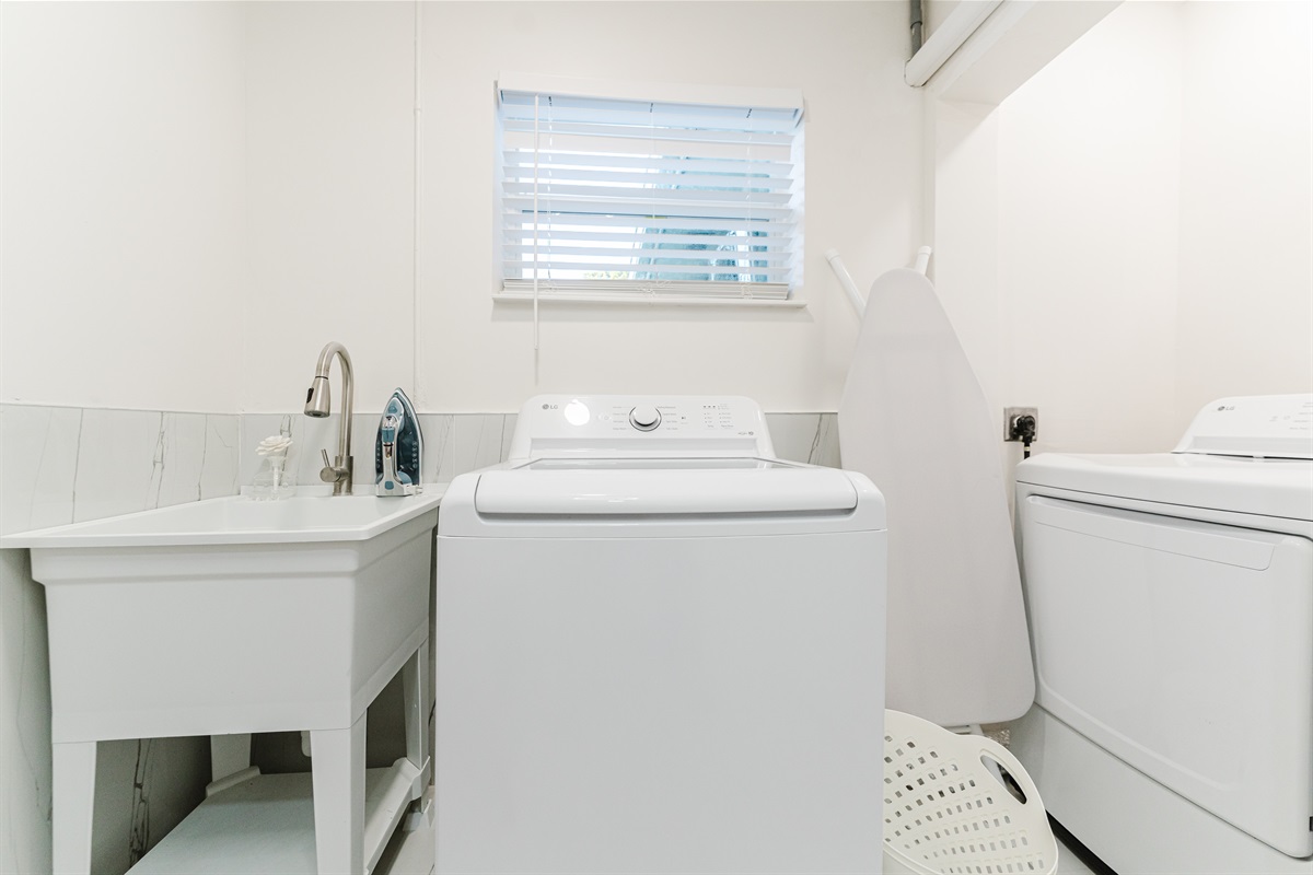 Bright, fully equipped laundry room with full-size washer & dryer, utility sink, iron, and ironing board for easy extended stays.
