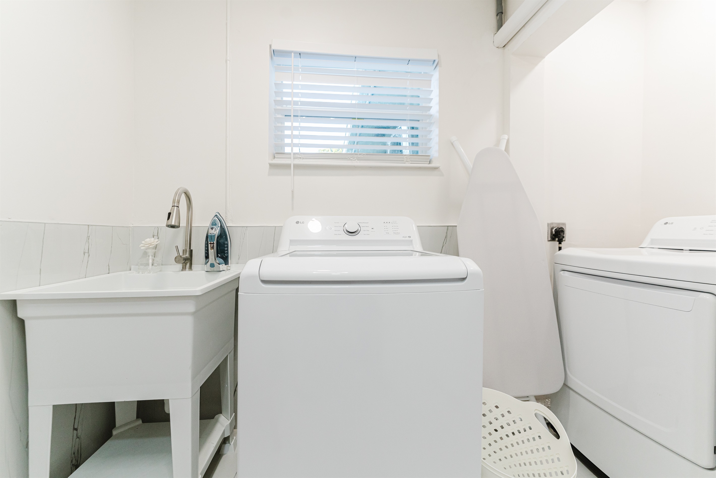 Bright, fully equipped laundry room with full-size washer & dryer, utility sink, iron, and ironing board for easy extended stays.