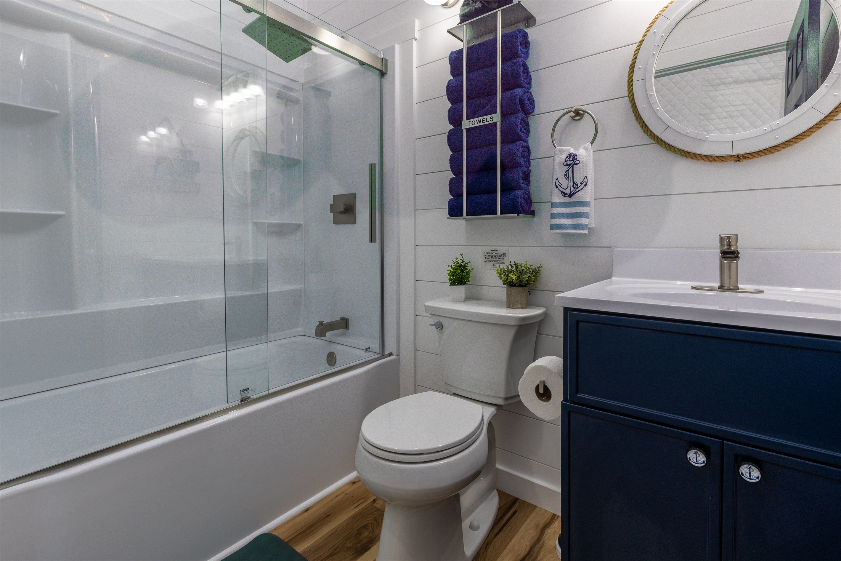 Bright, spotless bathroom with a full shower/tub combo, plush navy towels, and nautical touches for a comfortable stay