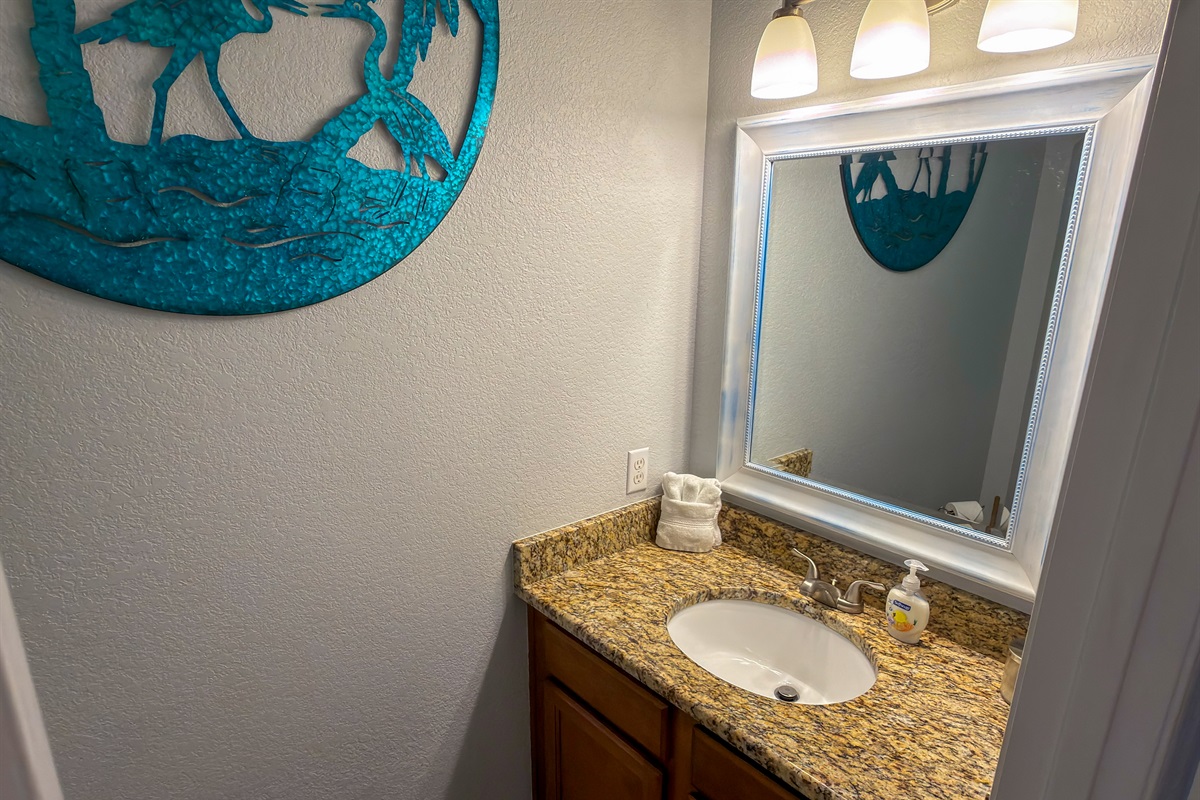 Located off the main hallway, the guest powder room is thoughtfully designed with warm lighting and upscale finishes.