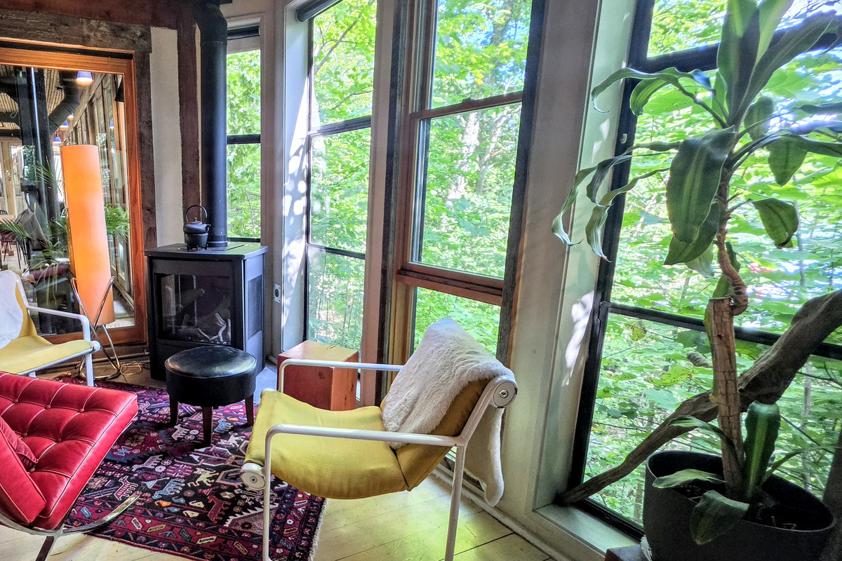 Seating around dining room stove with view into veranda
