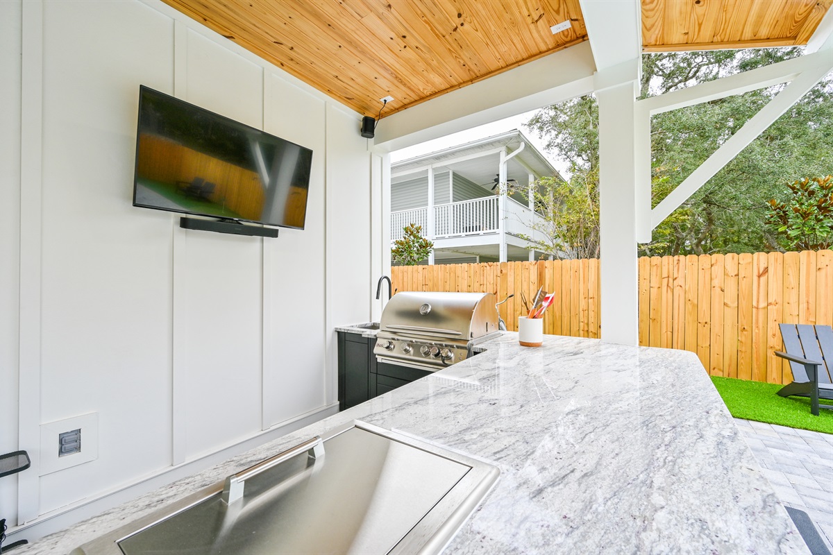 Summer Kitchen equipped with a 50" Smart TV, Surround Sound, ice box, and a Built-In Grill
