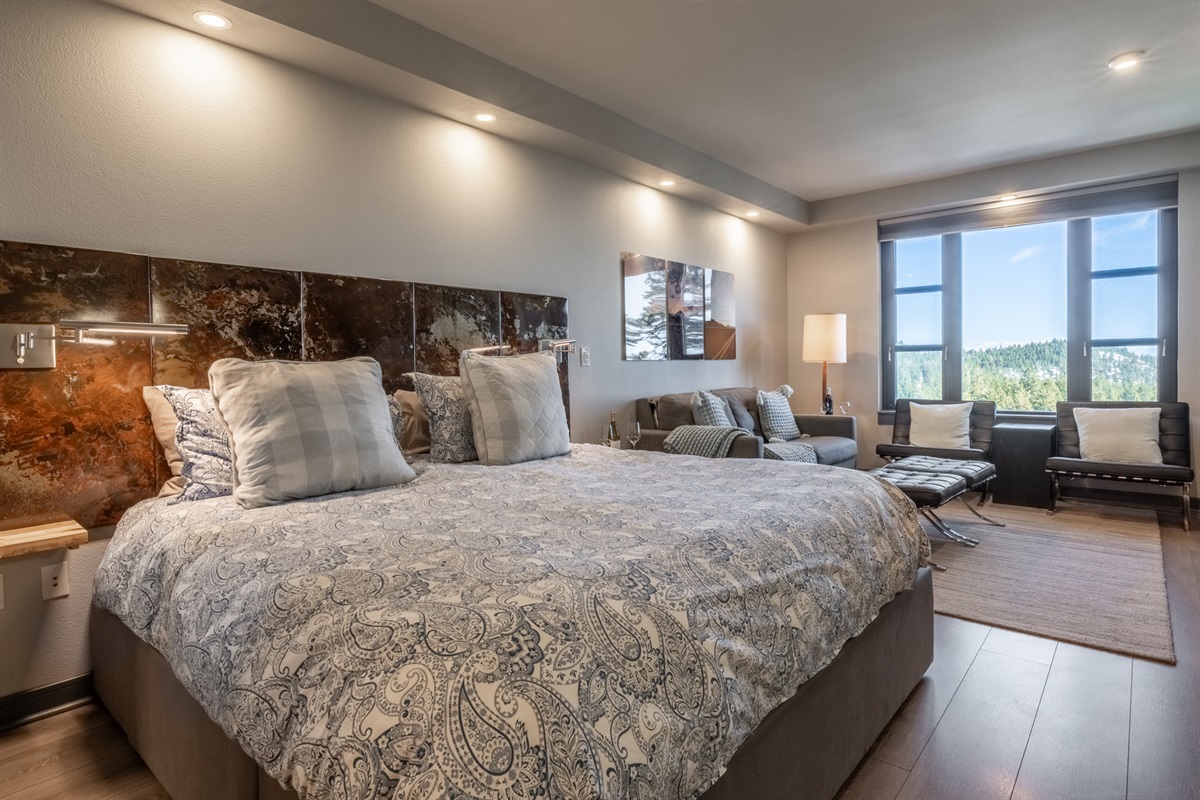 The king bed and living area share an open, airy layout that feels connected yet intentionally arranged for comfort.