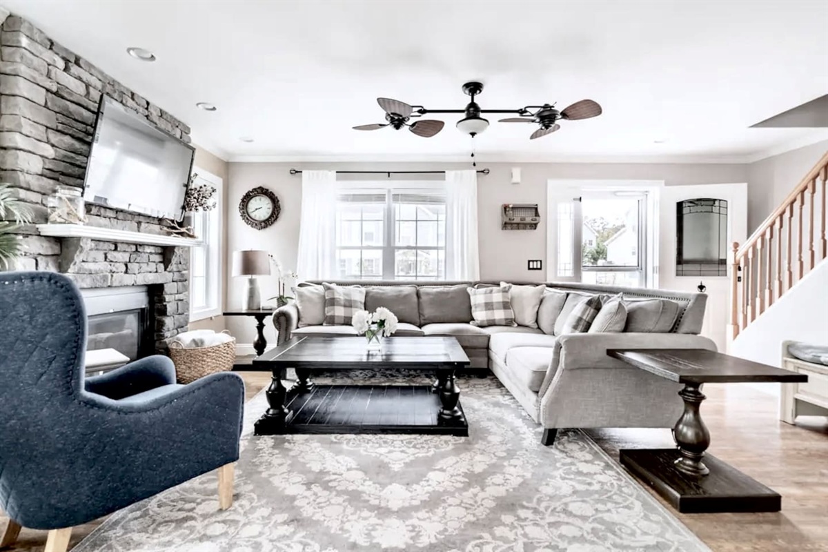 Gather in this bright, open living room for a cozy evening by the stone fireplace. Between the spacious sectional and the comfortable armchair, there is plenty of room for everyone to kick back and enjoy a movie or a quiet conversation.