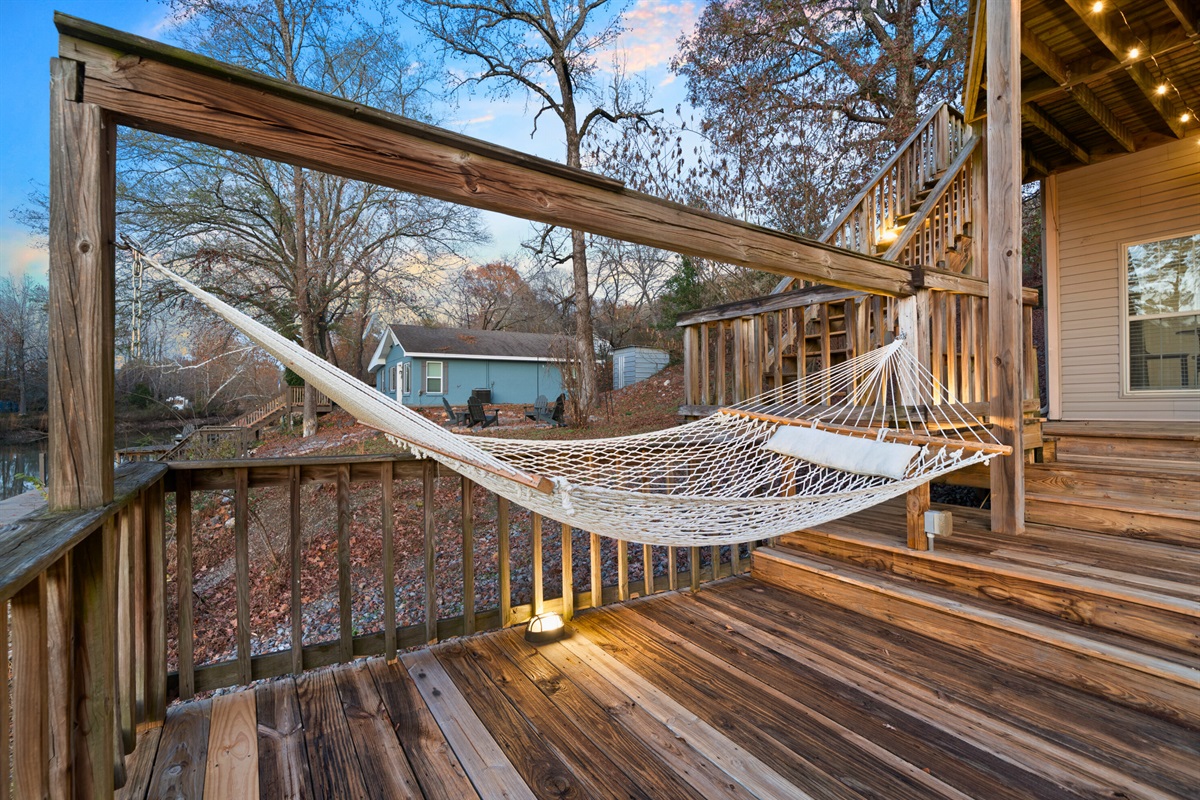The hammock sits tucked into a shaded corner of the deck, offering a dreamy spot to sway gently while taking in the sounds of nature all around you.