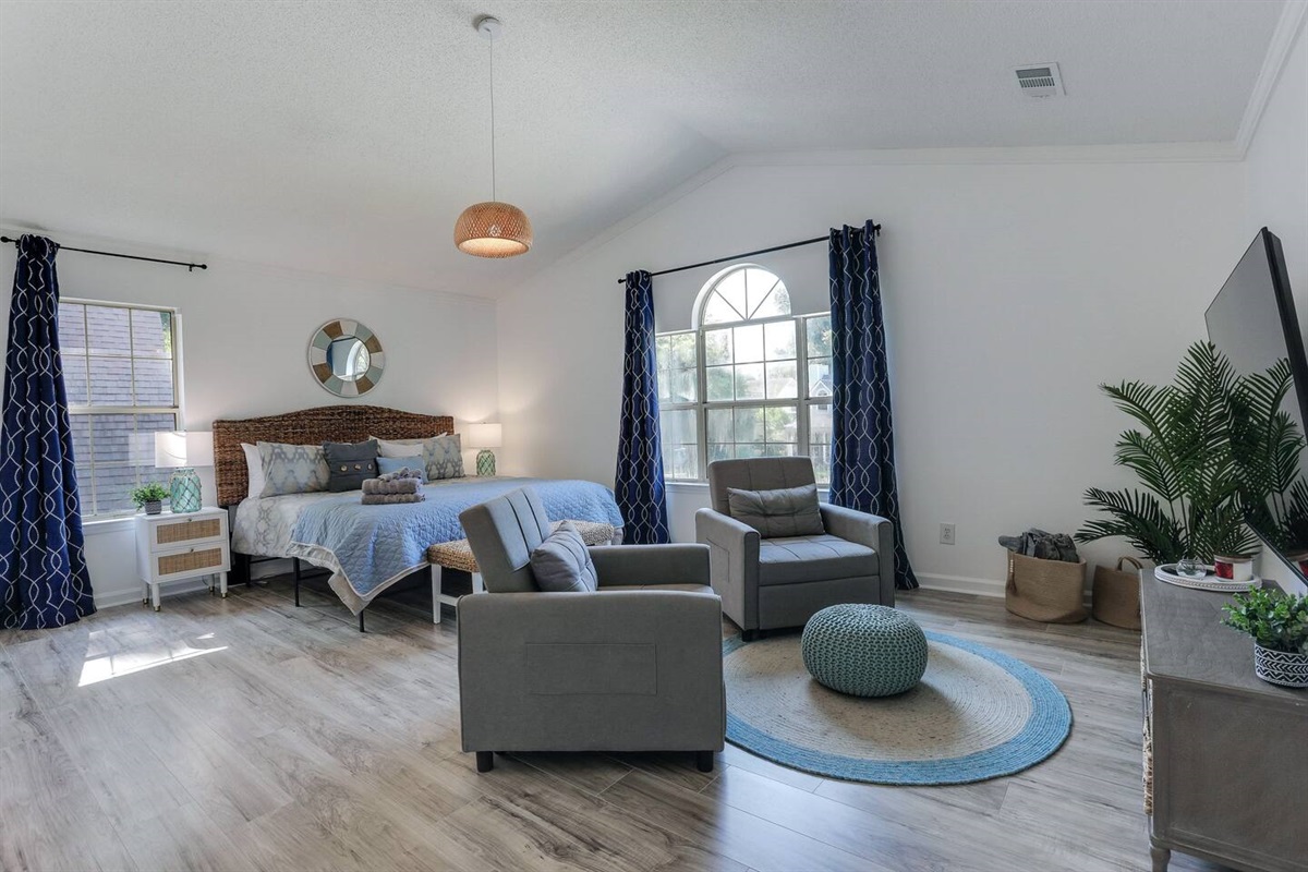 The primary bedroom is a relaxing retreat, complete with a luxurious king-sized bed, a smart TV for your entertainment, an ensuite bath for added privacy, and two cozy side chairs, perfect for unwinding after a day of exploring.