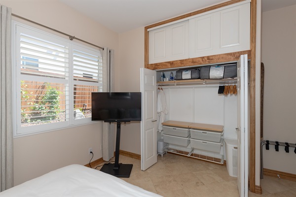 Open closet with hanging space, storage, and nearby TV