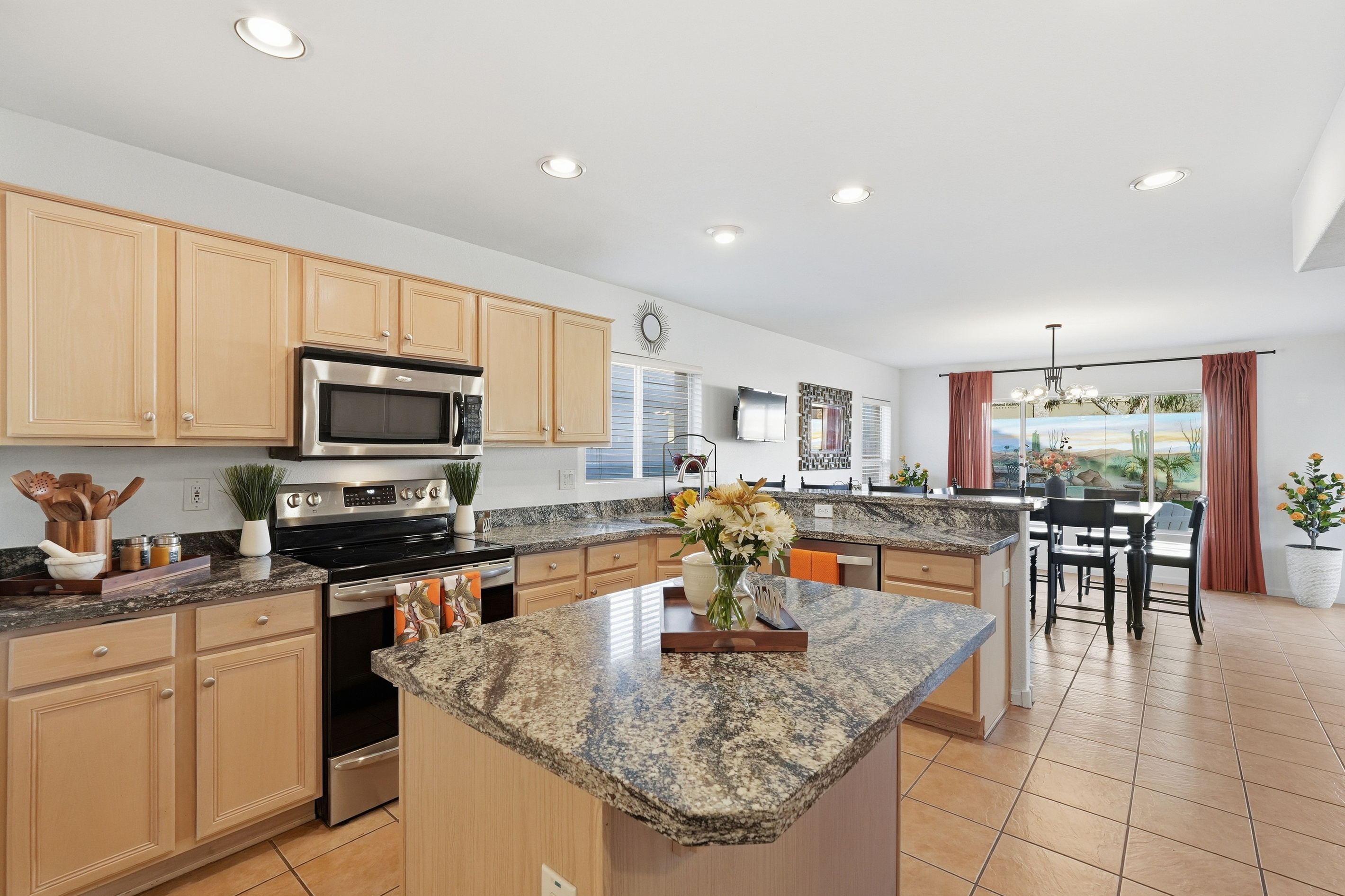 Full kitchen with island prep space, appliances, granite counters, and open flow into the dining area.