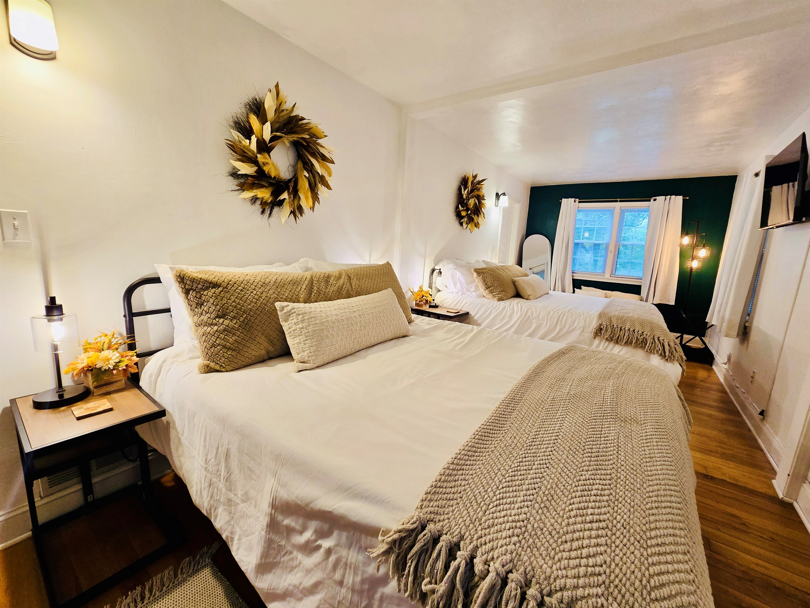 Feather wreaths crown each queen bed in the main bedroom, adding a soft, stylish touch. Fall-themed decor on the bedside tables, paired with cozy blankets and plush pillows, create a space that’s both inviting and seasonally inspired