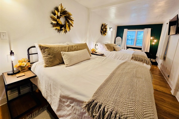 Feather wreaths crown each queen bed in the main bedroom, adding a soft, stylish touch. Fall-themed decor on the bedside tables, paired with cozy blankets and plush pillows, create a space that’s both inviting and seasonally inspired