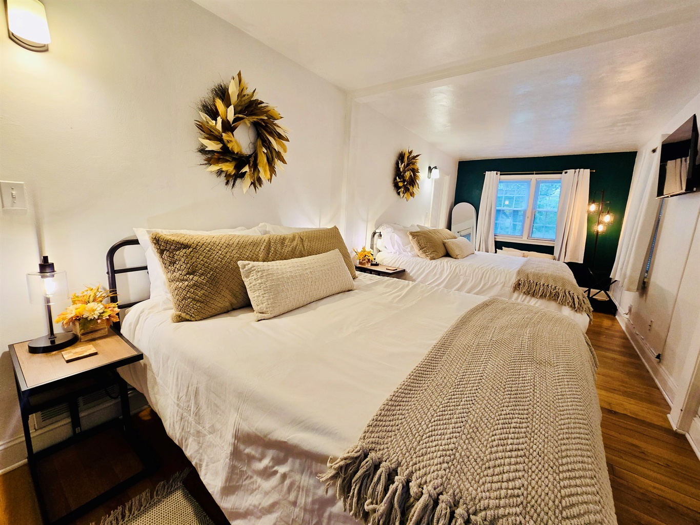 Feather wreaths crown each queen bed in the main bedroom, adding a soft, stylish touch. Fall-themed decor on the bedside tables, paired with cozy blankets and plush pillows, create a space that’s both inviting and seasonally inspired