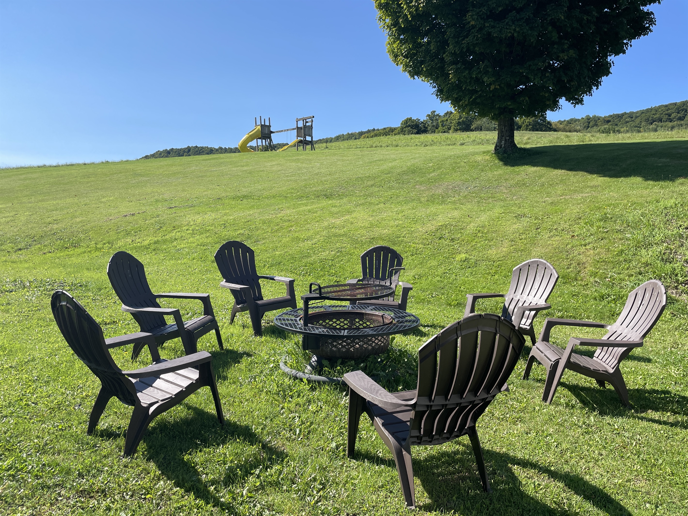 Roundtripper firepit with large lawn view and a swing set on the hill for the little ones in your group.