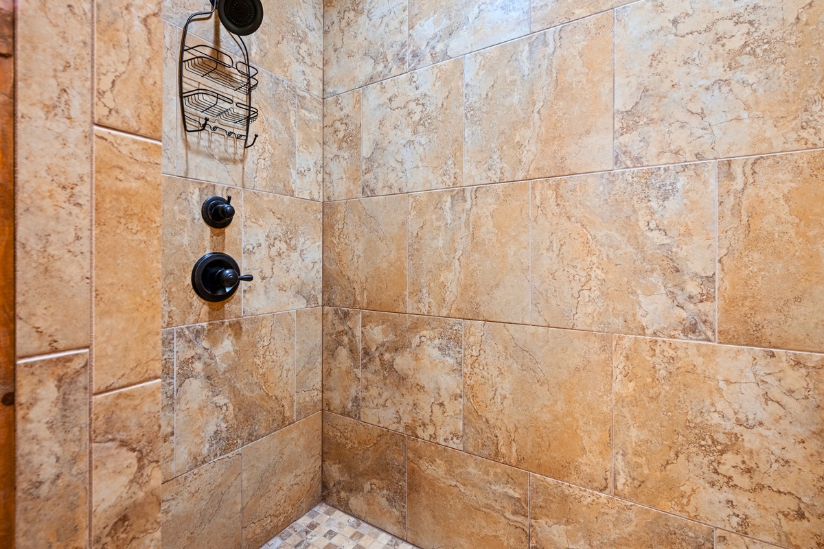 The walk-in shower offers a clean, modern space with stone-style tile and plenty of room to refresh after outdoor adventures.