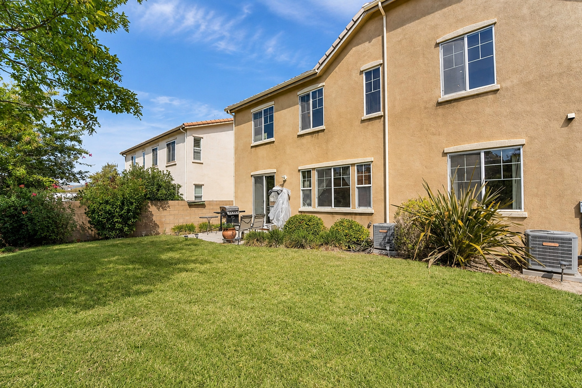 Backyard with a grassy lawn, patio seating, and plenty of space to enjoy the fresh air.