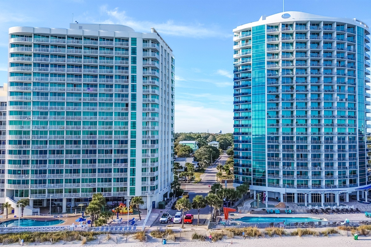 - Oceanfront resort building exterior featuring tall windows and unique blue trim   - Modern architecture highlights Myrtle Beach skyline with contemporary coastal look   - Vacation stay offer