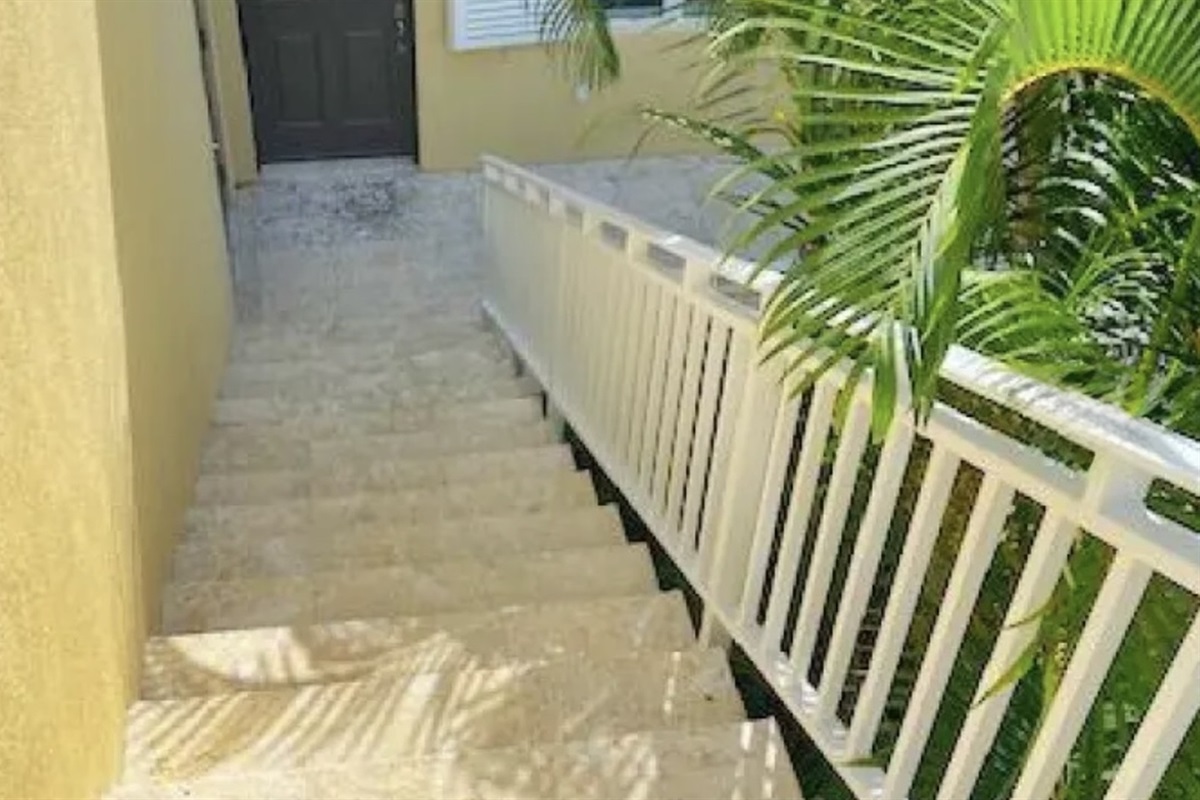 Easy-access entry with wide steps and tropical landscaping—private and peaceful fifth bedroom