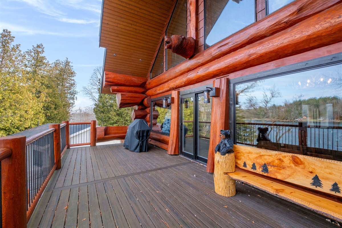 Spacious upper deck with BBQ, carved log décor, and unobstructed forest and lake views.
