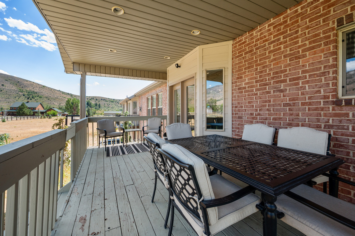 The spacious covered deck features a full outdoor dining table and additional seating, creating an inviting setting for meals and conversation with a view.