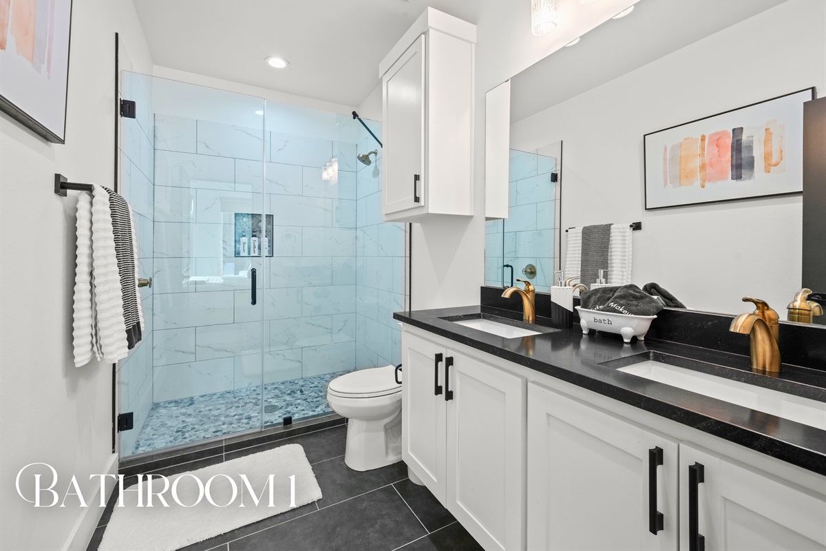 The first full bathroom features a clean, modern design with a spacious walk-in shower and sleek finishes throughout.