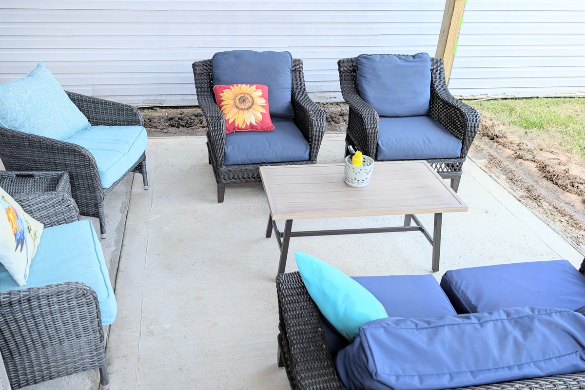 The covered patio offers plush seating and a fenced courtyard, creating a comfortable and private outdoor space to relax.