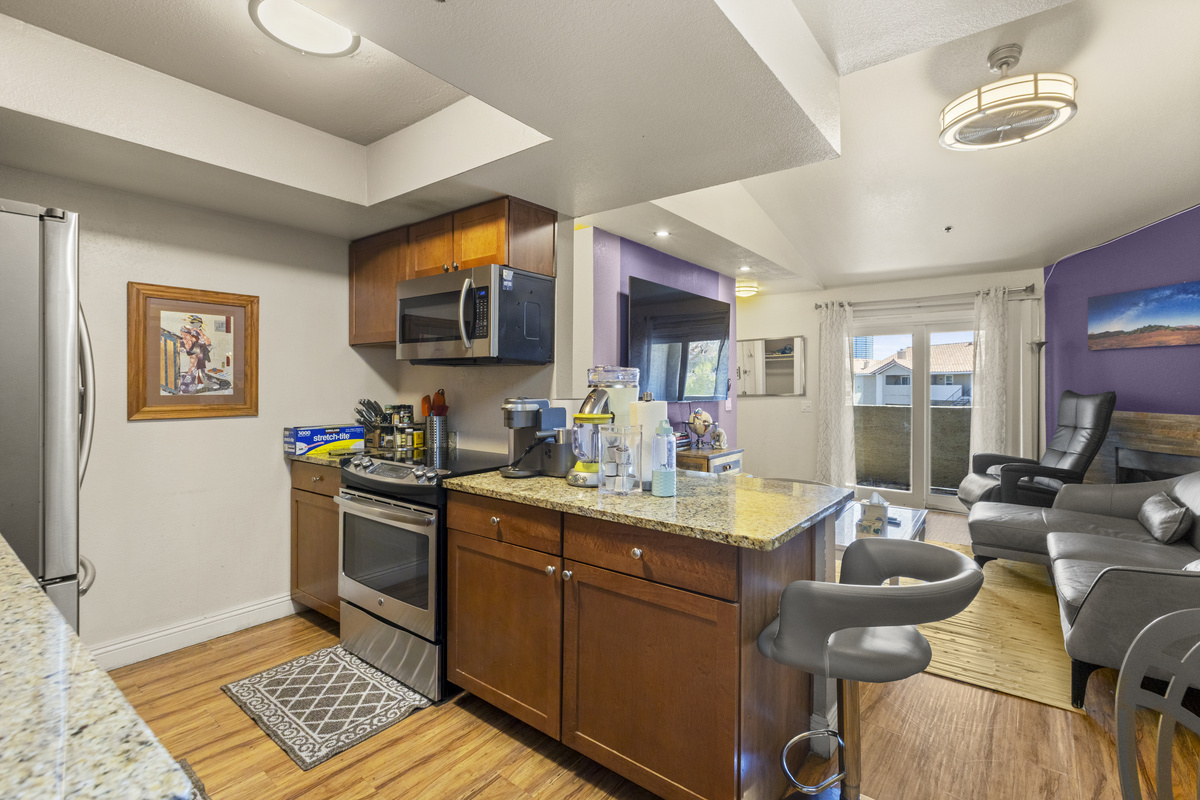 Kitchen with granite counters, coffee station, full appliances, and a clear view into the living area.
