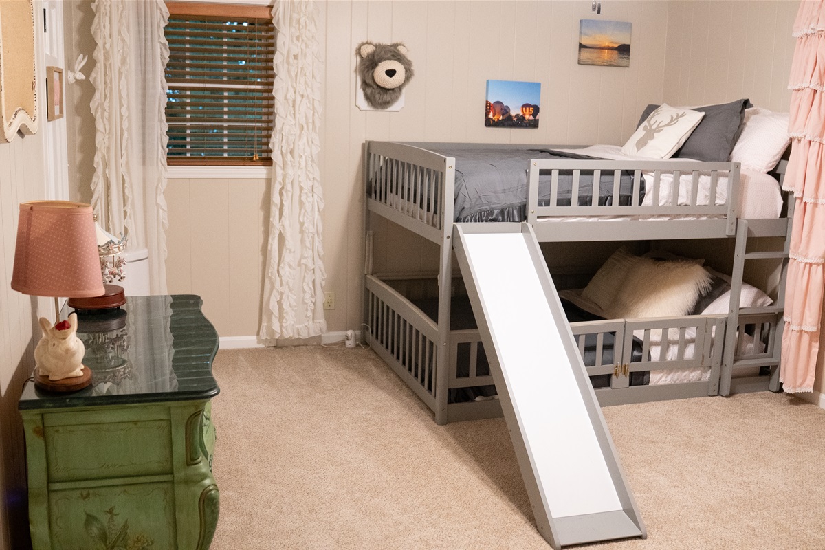This upstairs bedroom features full-over-full bunk beds, a cozy rocking chair, and a spacious walk-in closet.