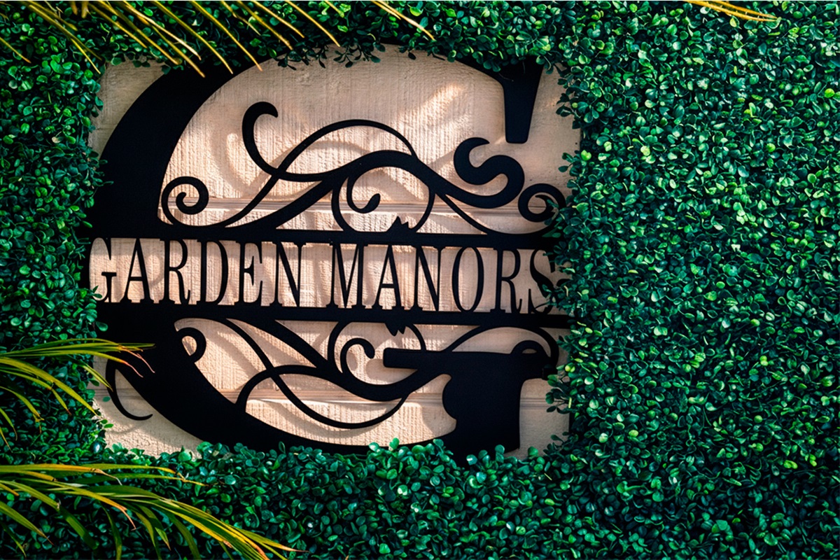 Garden of Manors entrance sign framed by lush greenery, setting the tone for a private boutique stay in Wilton Manors.