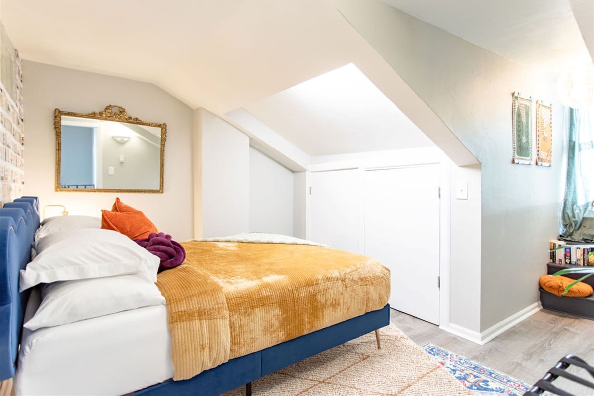 Relax in this inviting bedroom featuring a comfortable queen bed with four sumptuous pillows. The vintage mirror adds a touch of timeless charm, and the cozy reading nook is perfect for curling up with a good book. This beautifully designed space com