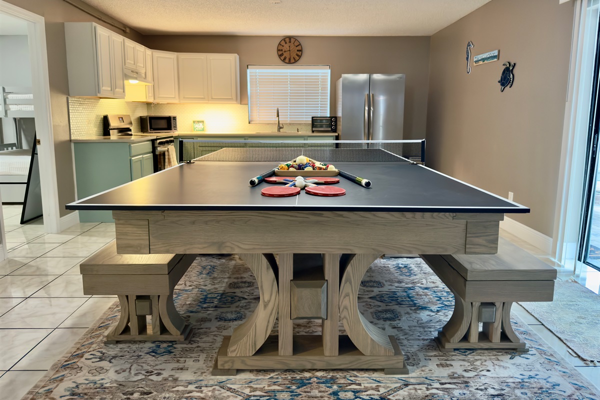 At the center of the room is a modern farmhouse-style table that transforms effortlessly from a dining space to a full-size ping pong table.
