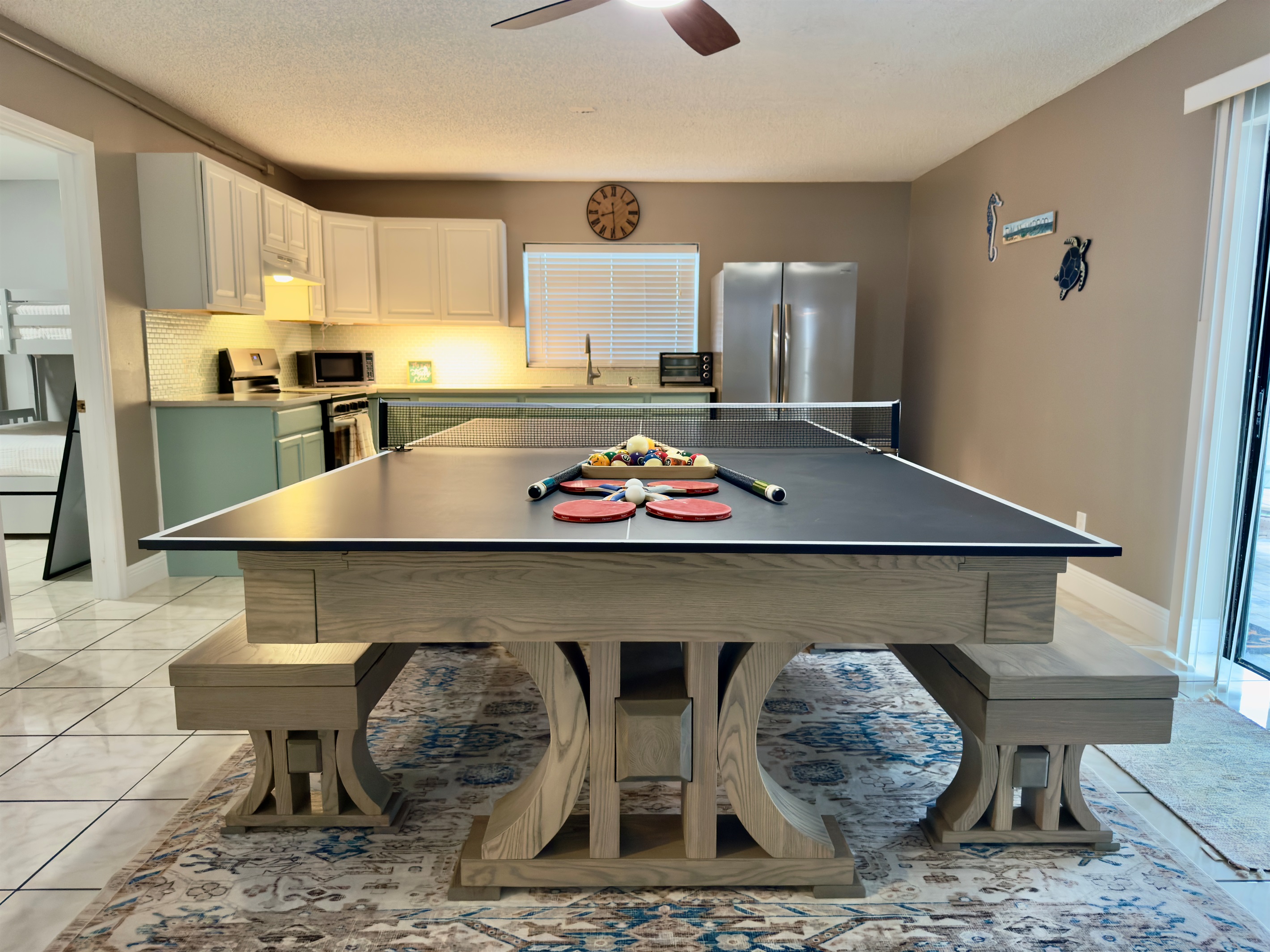 At the center of the room is a modern farmhouse-style table that transforms effortlessly from a dining space to a full-size ping pong table.