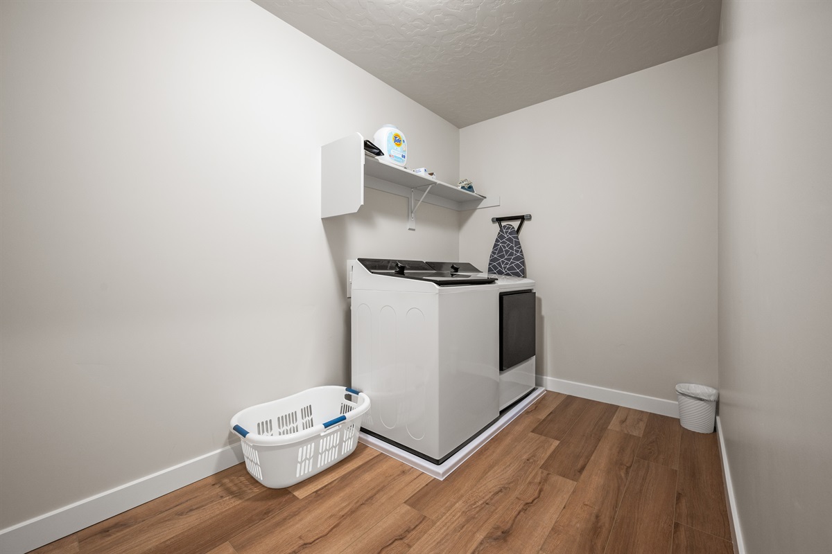 Keep your wardrobe crisp and clean with a full laundry setup, including a washer, dryer, basket, iron, and ironing board.