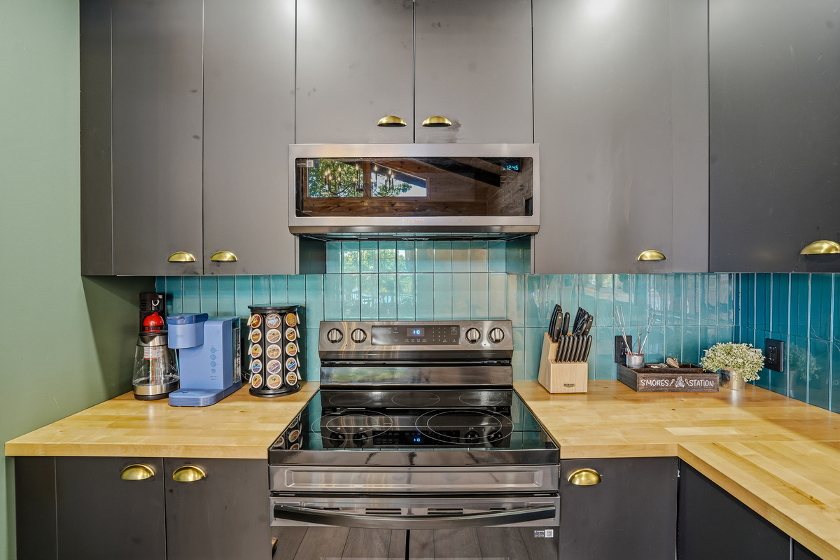 Kitchen cooking station — stainless range, microwave, and teal tile backsplash