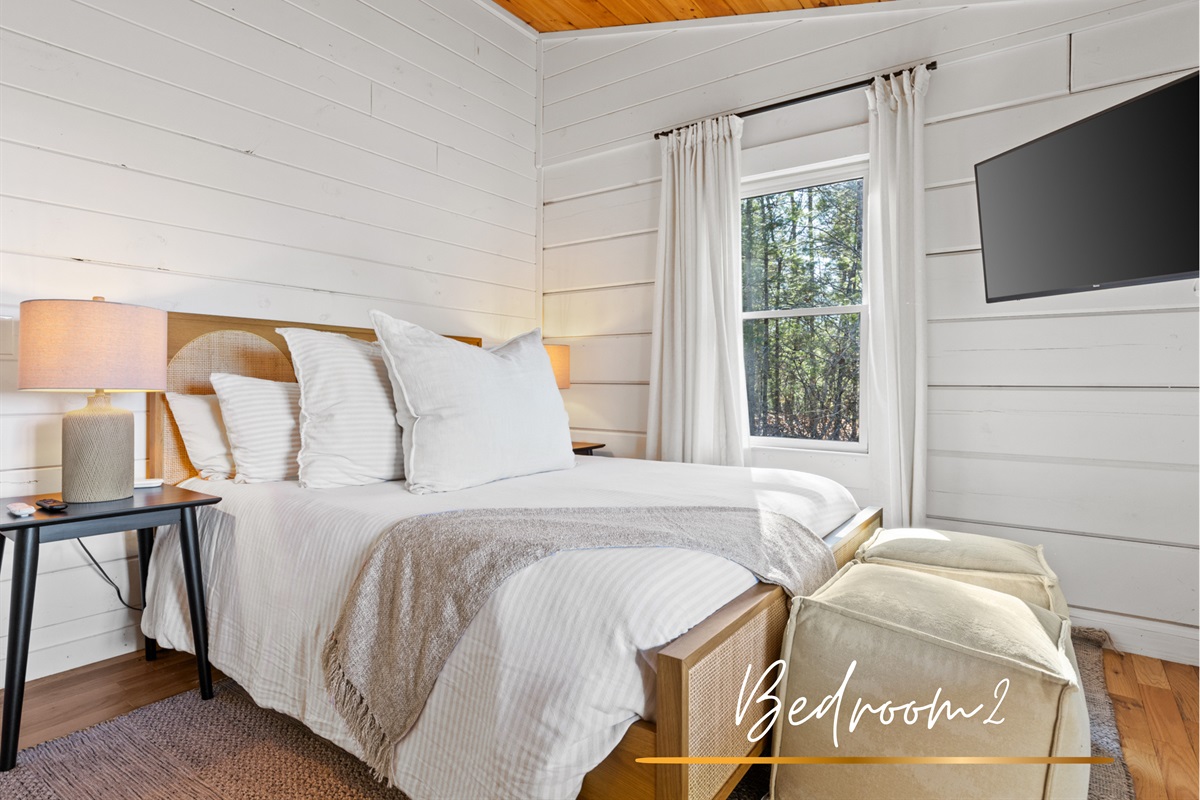 Cozy and inviting bedroom, featuring a queen-sized bed, natural wood accents, and serene forest views, perfect for a relaxing getaway.