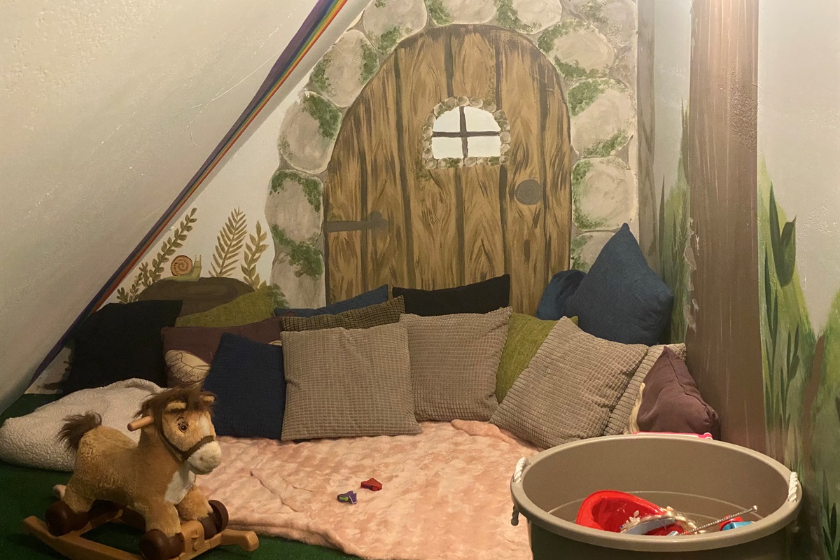 A cozy little play area for littles. There are toys and book and plenty of cushions to cozy up on and take a nap