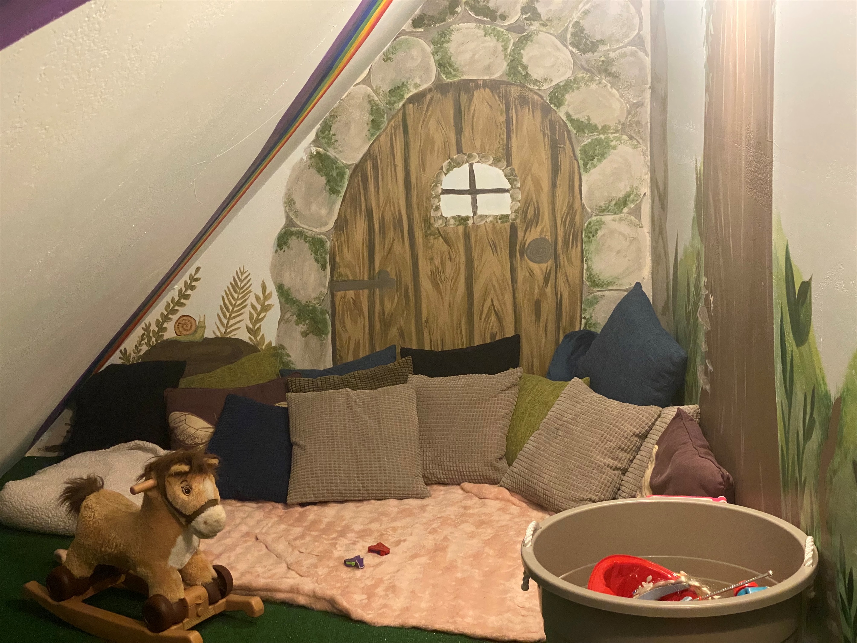 A cozy little play area for littles. There are toys and book and plenty of cushions to cozy up on and take a nap