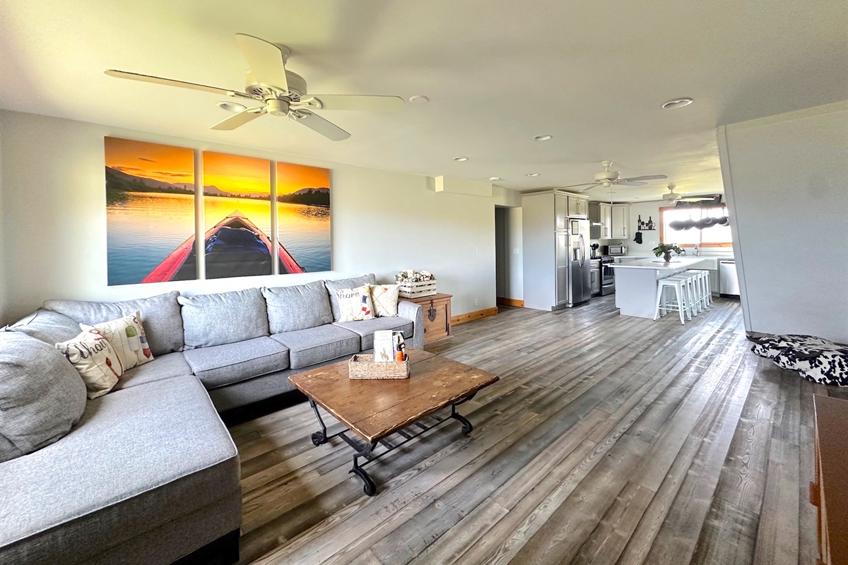 Living room in Unit B with a large TV, comfortable sectional sofa, and a cozy wood-burning stove.