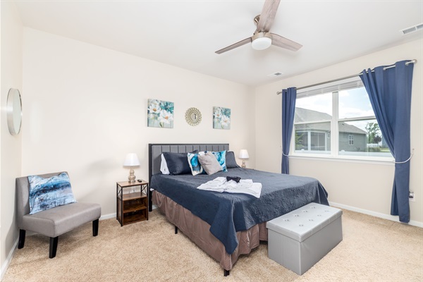 Tranquil primary suite with a plush king-size bed, cozy seating area, and USB chargers at the nightstand—your restful retreat after a day of sun and surf.