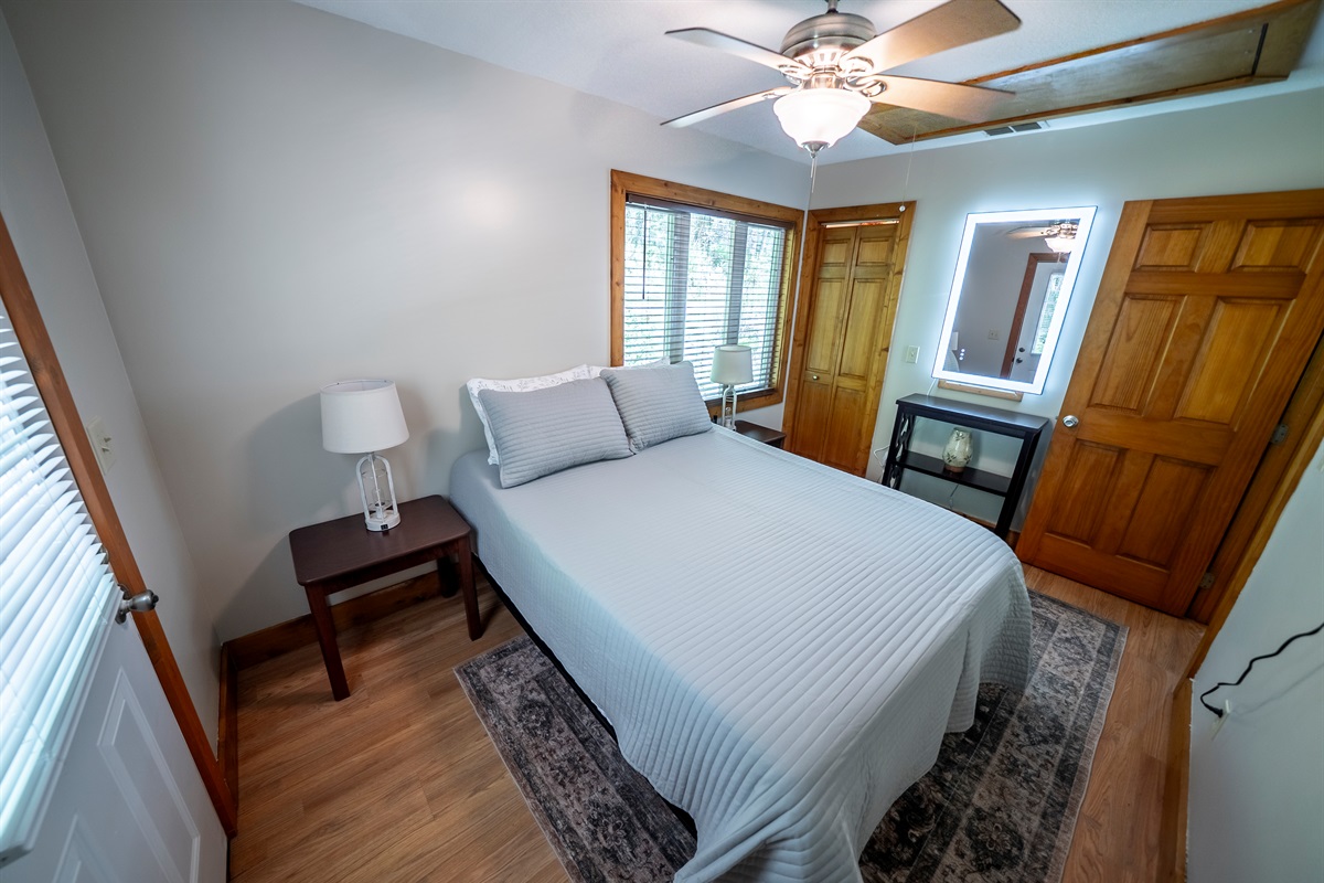 Thoughtfully designed guest room with a queen bed, LED-lit mirror for easy mornings, Smart TV, ceiling fan, and deck access.