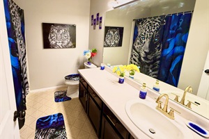 The bathroom features a sleek, modern aesthetic with clean lines and a neutral color palette. A striking black and white tiger painting adds drama and personality to the space. 