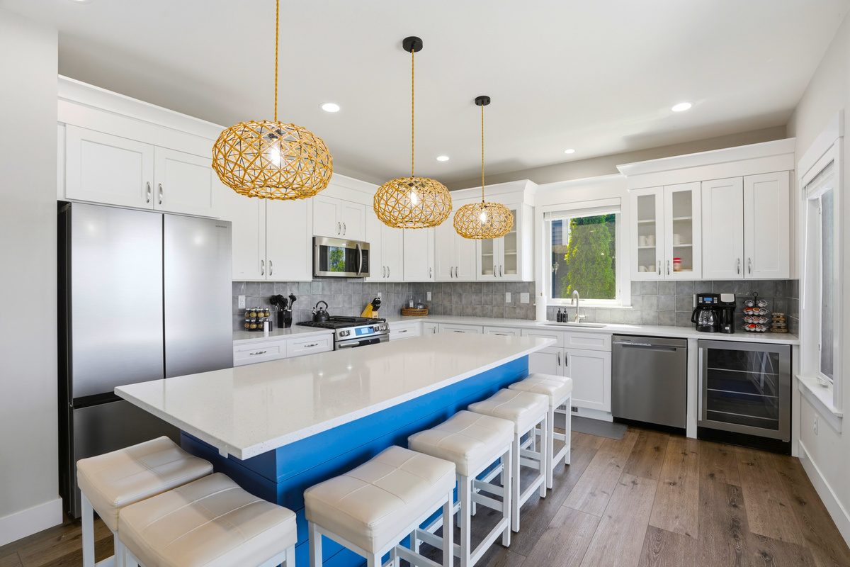 Fully stocked, modern kitchen featuring an oversized island with seating, stainless-steel appliances, coffee bar, and plenty of space for cooking and gathering.