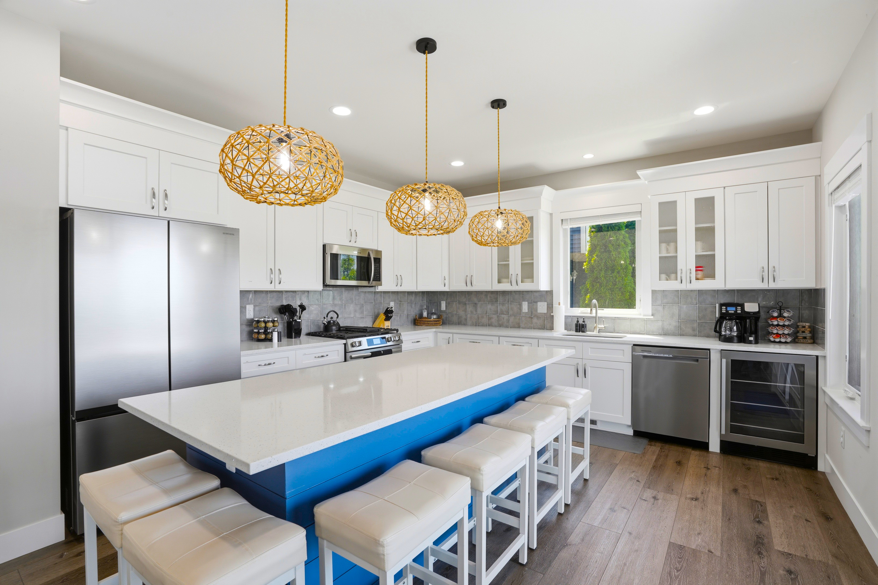 Fully stocked, modern kitchen featuring an oversized island with seating, stainless-steel appliances, coffee bar, and plenty of space for cooking and gathering.