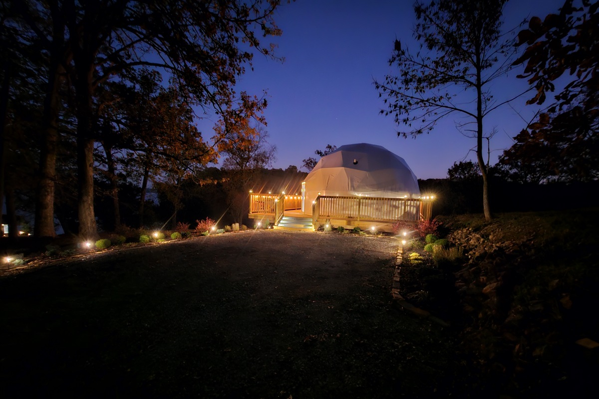 Warm, inviting nighttime arrival with pathway lighting and a private deck overlooking the lake