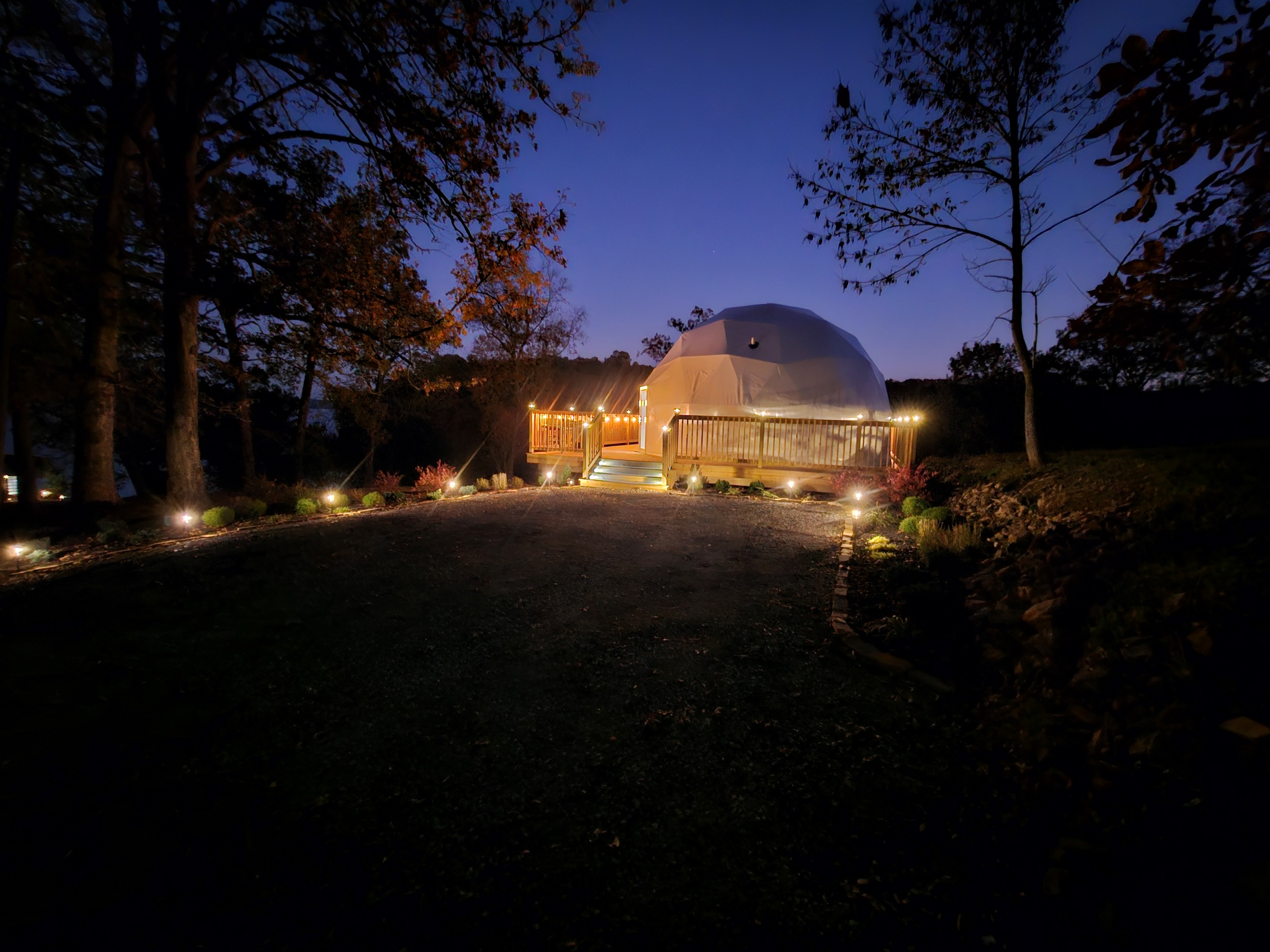 Warm, inviting nighttime arrival with pathway lighting and a private deck overlooking the lake