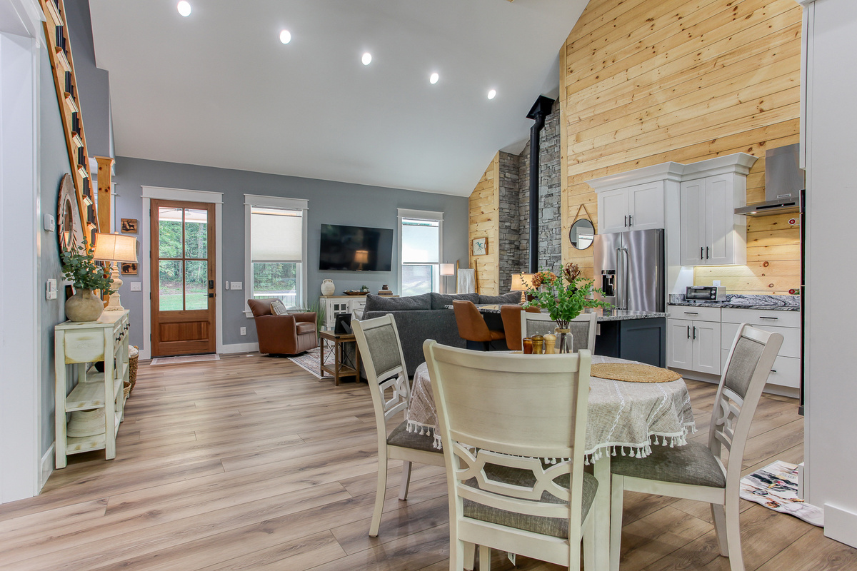 The open layout at Robbin’s Nest on Snowbird Creek keeps the dining area, kitchen, and living room connected beneath a vaulted ceiling.