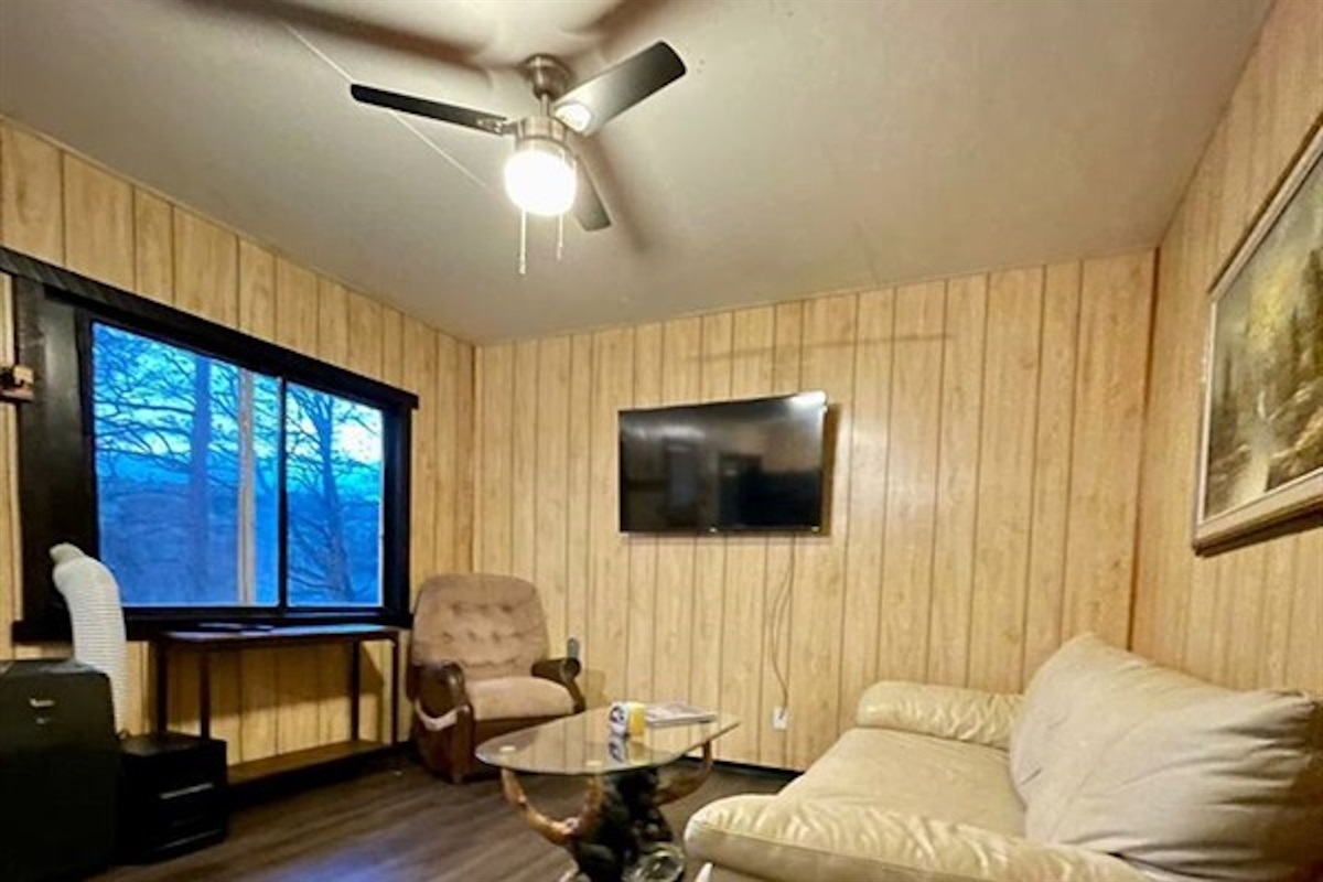 Bright lounge area with large window and ceiling fan