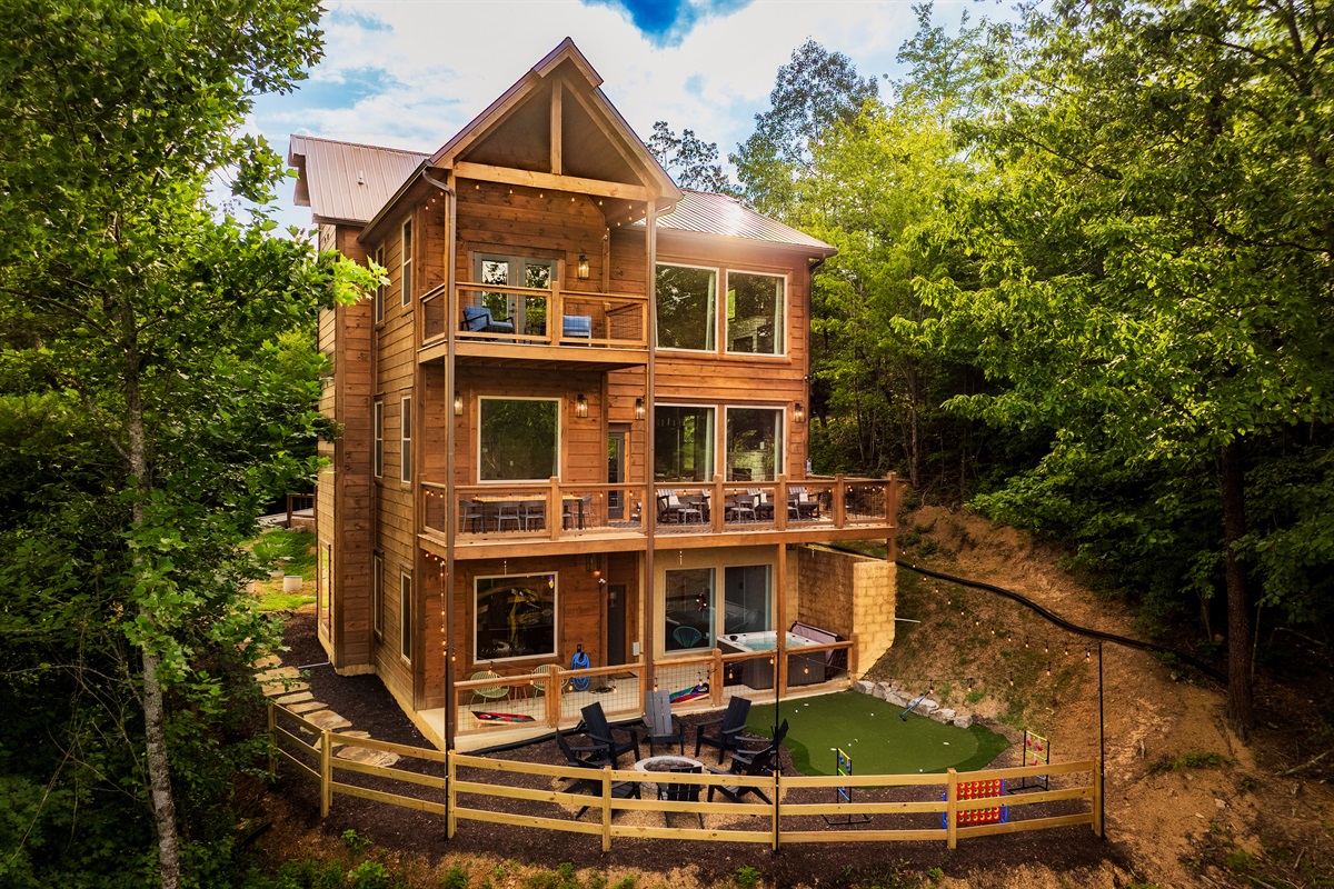 Luxury cabin with multiple decks, hot tub, and backyard with string lights, fire pit and mini golf