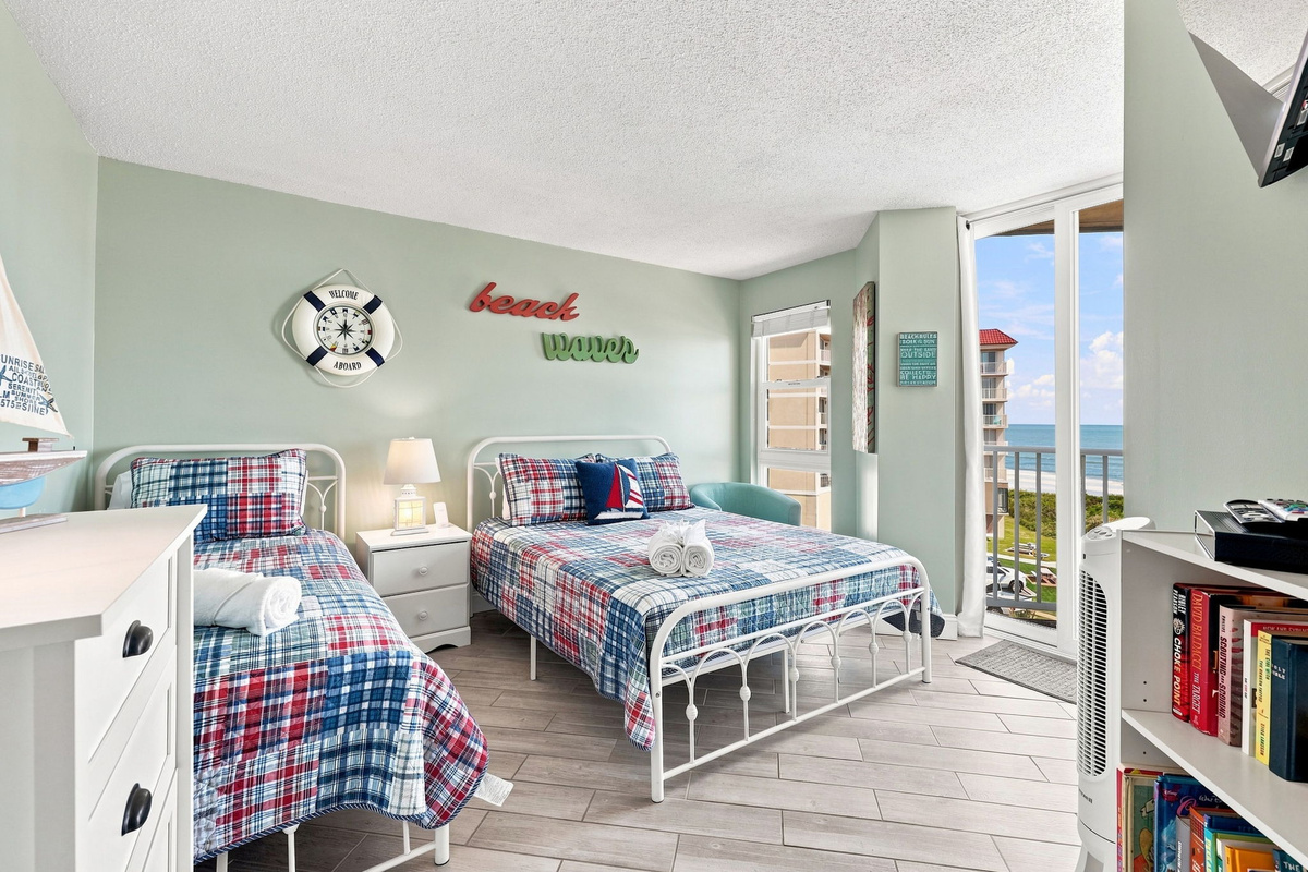 Charming guest room outfitted with beach-inspired accents, crisp white furnishings, and sliding glass doors that let in plenty of natural light.