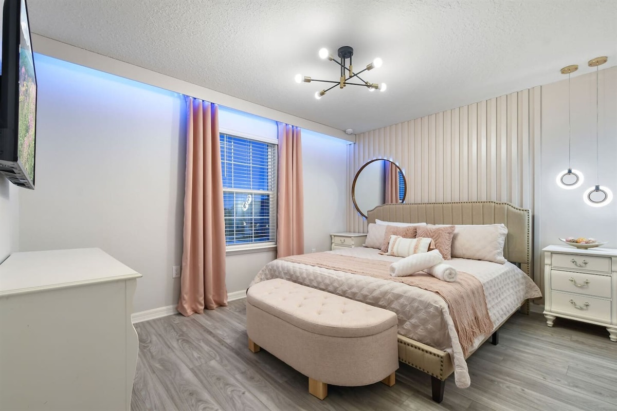 Elegantly designed, this king bedroom shares a Jack-and-Jill bathroom with the Tangled Room. The bathroom includes a stand-up shower and a stylish round mirror. Includes a smart TV.