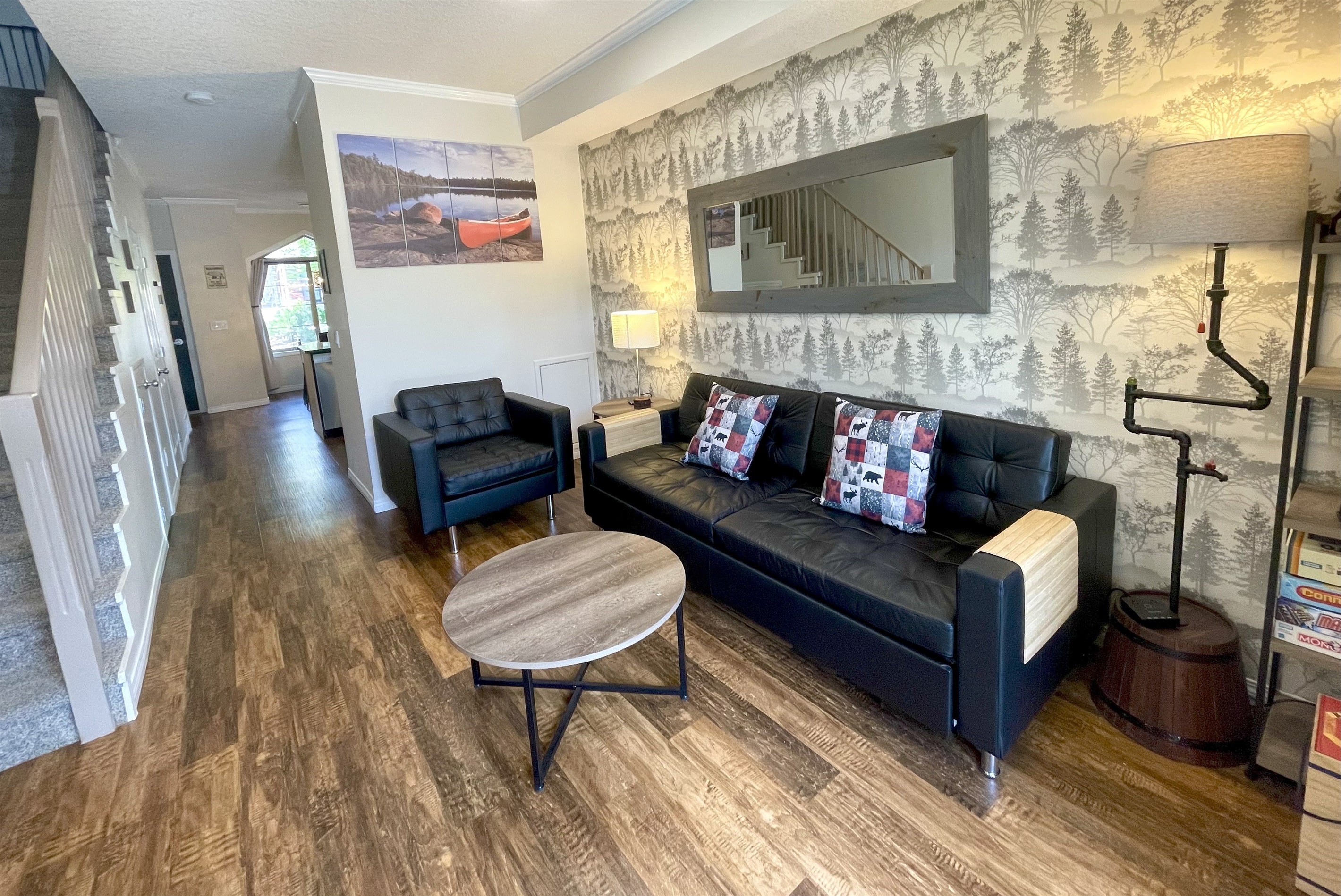 Living room, connected to the kitchen and dining in the back. Stairs to 2nd level visible on the left. Queen Sofabed on the right.